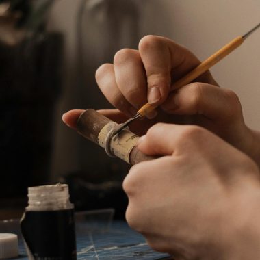 Hands of a Person Holding a Wooden Tube and a Jewelry Making Tool